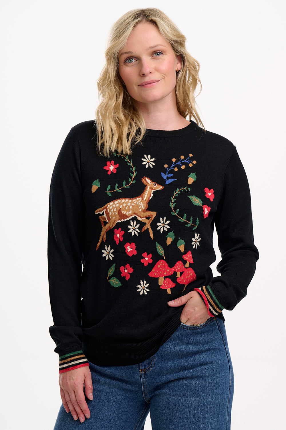 Woman wearing a black sweater with floral and deer design on a white background