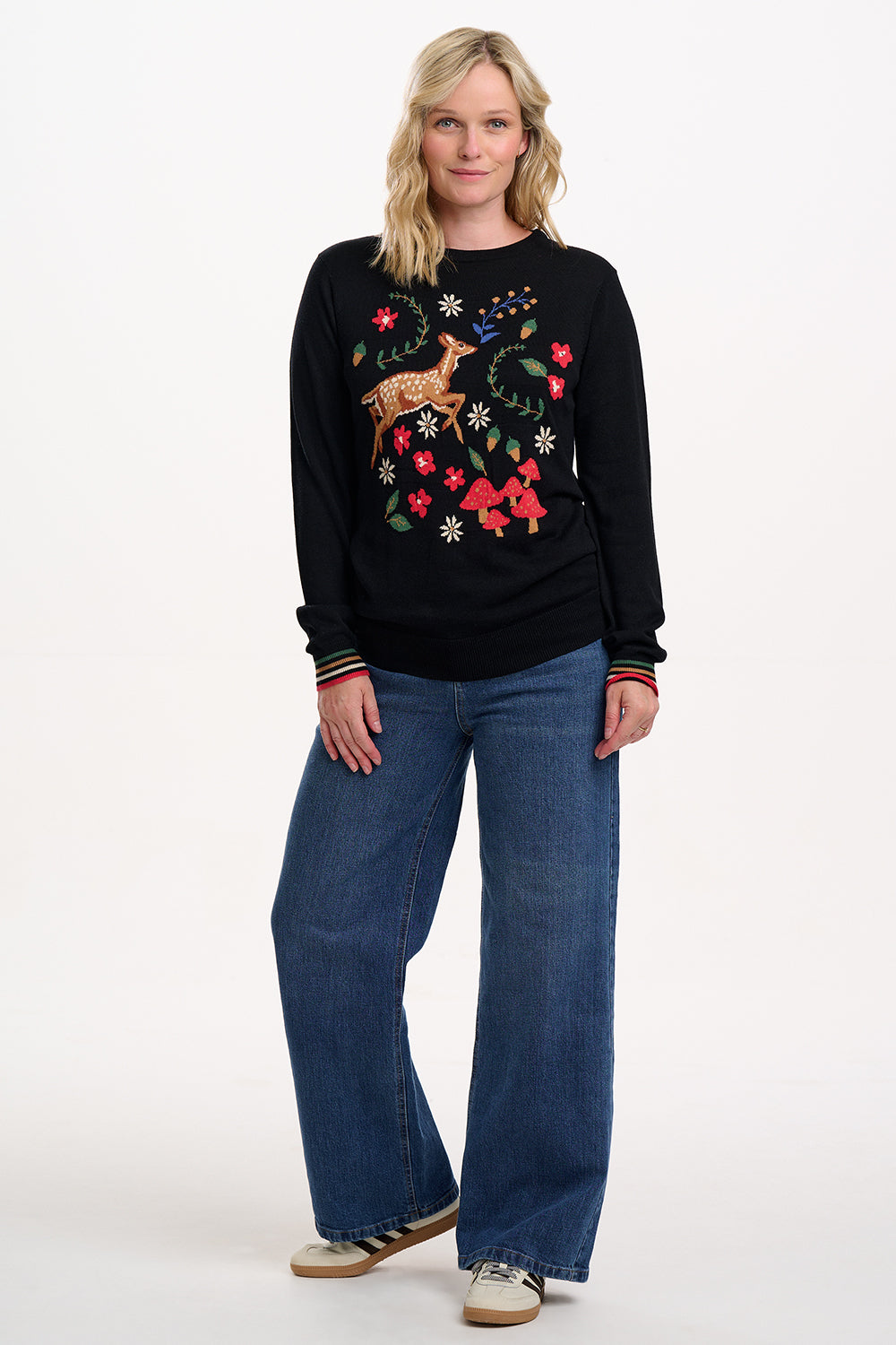 Woman wearing a black sweater with a festive design on a white background