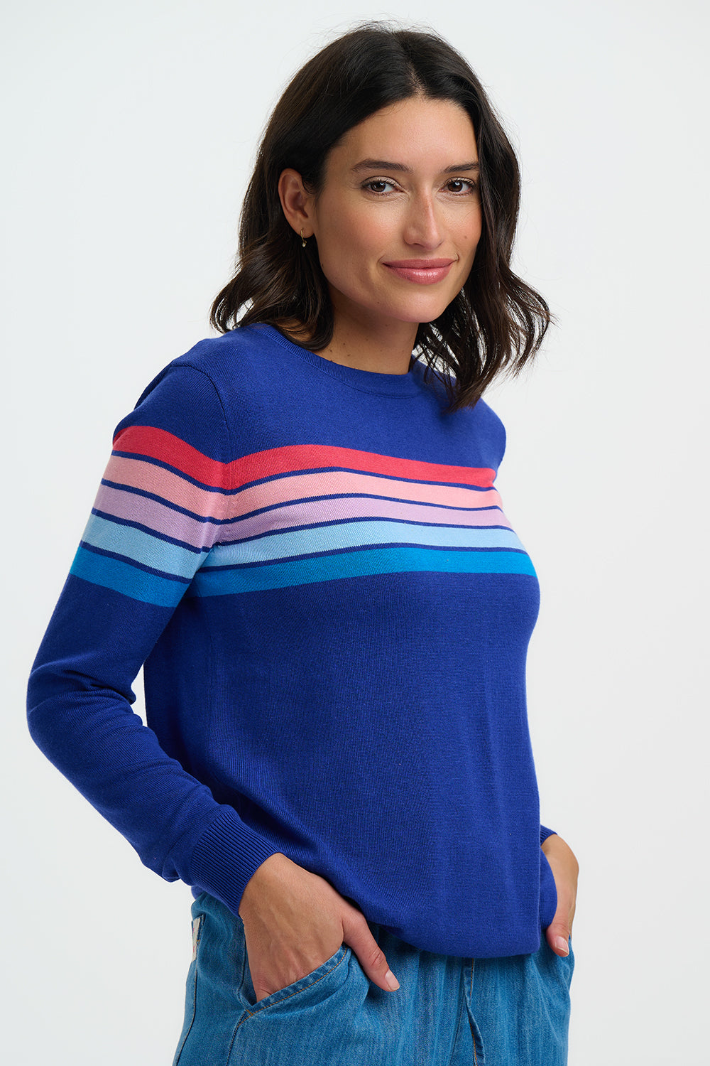 Woman wearing a blue sweater with colorful stripes on a white background