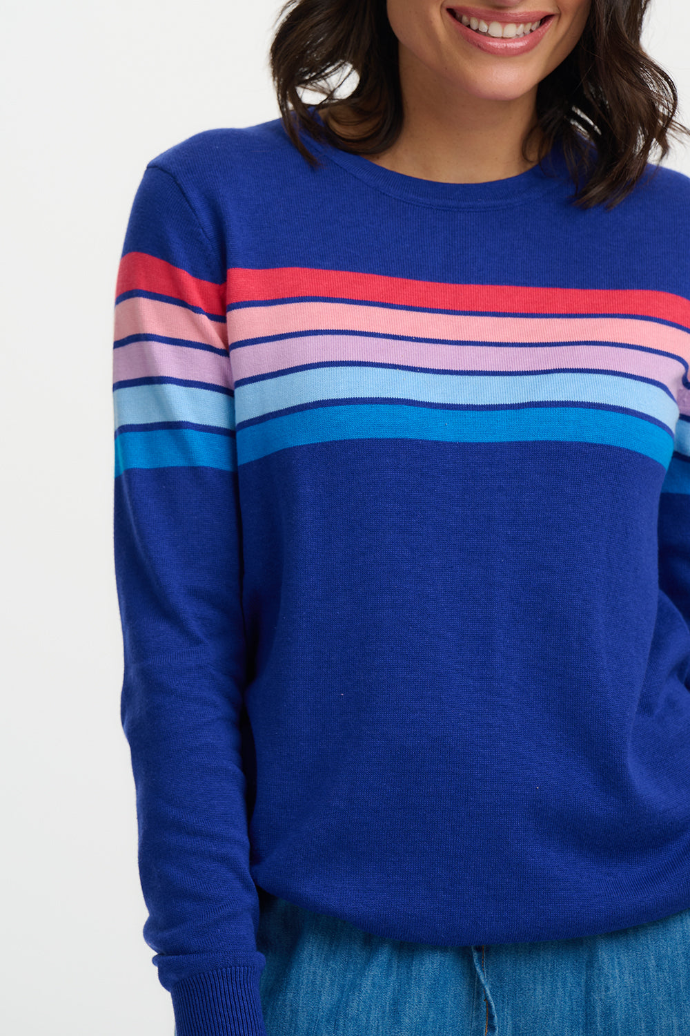 Blue sweater with colorful stripes worn by a person on a white background