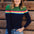 A woman wearing a navy and green color-blocked jumper with a rainbow split design across the chest, paired with blue jeans.