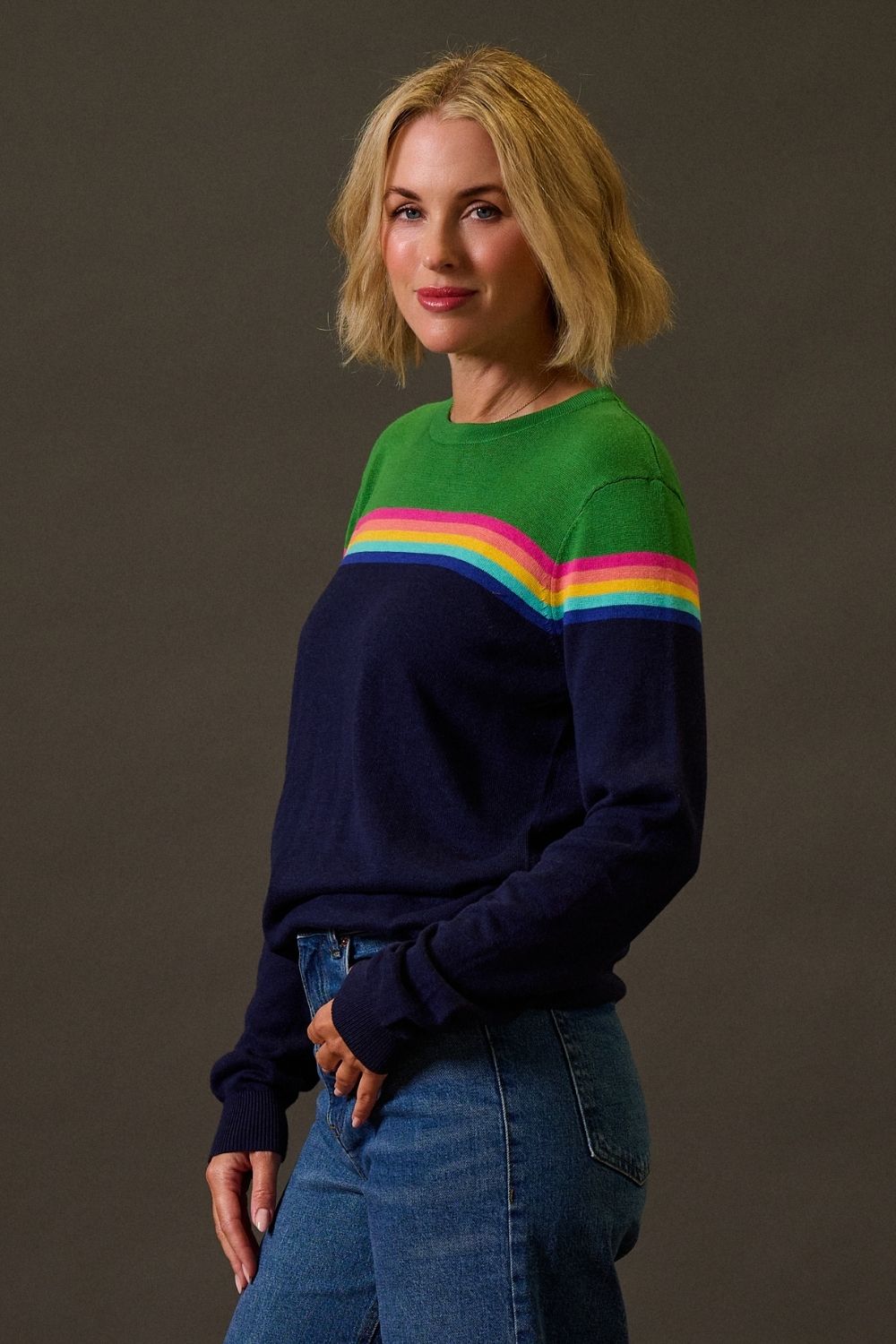 Woman wearing a colorful sweater with a striped pattern against a plain background