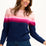 Sugarhill Brighton model wearing a navy jumper with pink gradient stripes, paired with jeans, standing against a white background.