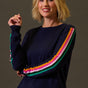 Woman wearing a navy sweater with colorful stripes on a brown background
