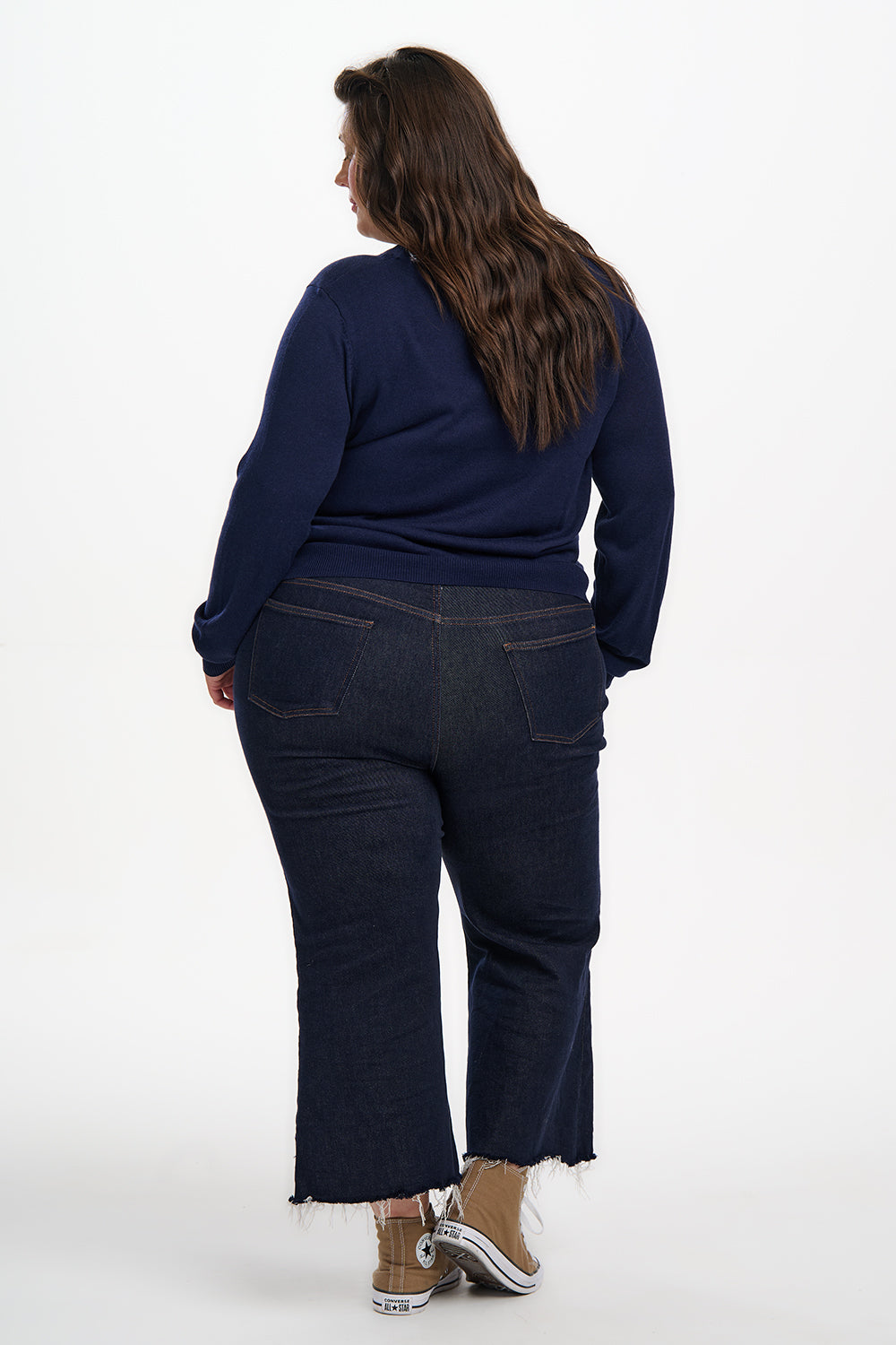 Person wearing navy blue sweater and jeans on a white background