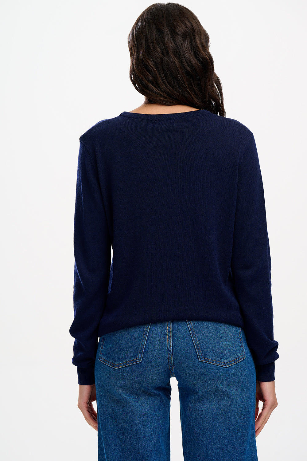 Woman wearing a navy sweater with a graphic design and blue jeans.