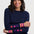 Woman wearing a navy sweater with colorful star patterns on sleeves against a white background
