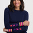 Woman wearing a navy sweater with colorful star patterns on sleeves against a white background