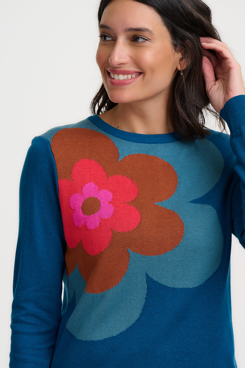 Woman wearing a blue sweater with a colorful flower design on a white background