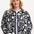 A woman wearing a monochrome quilted jacket with a floral folk print, featuring white leaves and flowers on a black base.