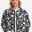 A woman wearing a monochrome quilted jacket with a floral folk print, featuring white leaves and flowers on a black base.