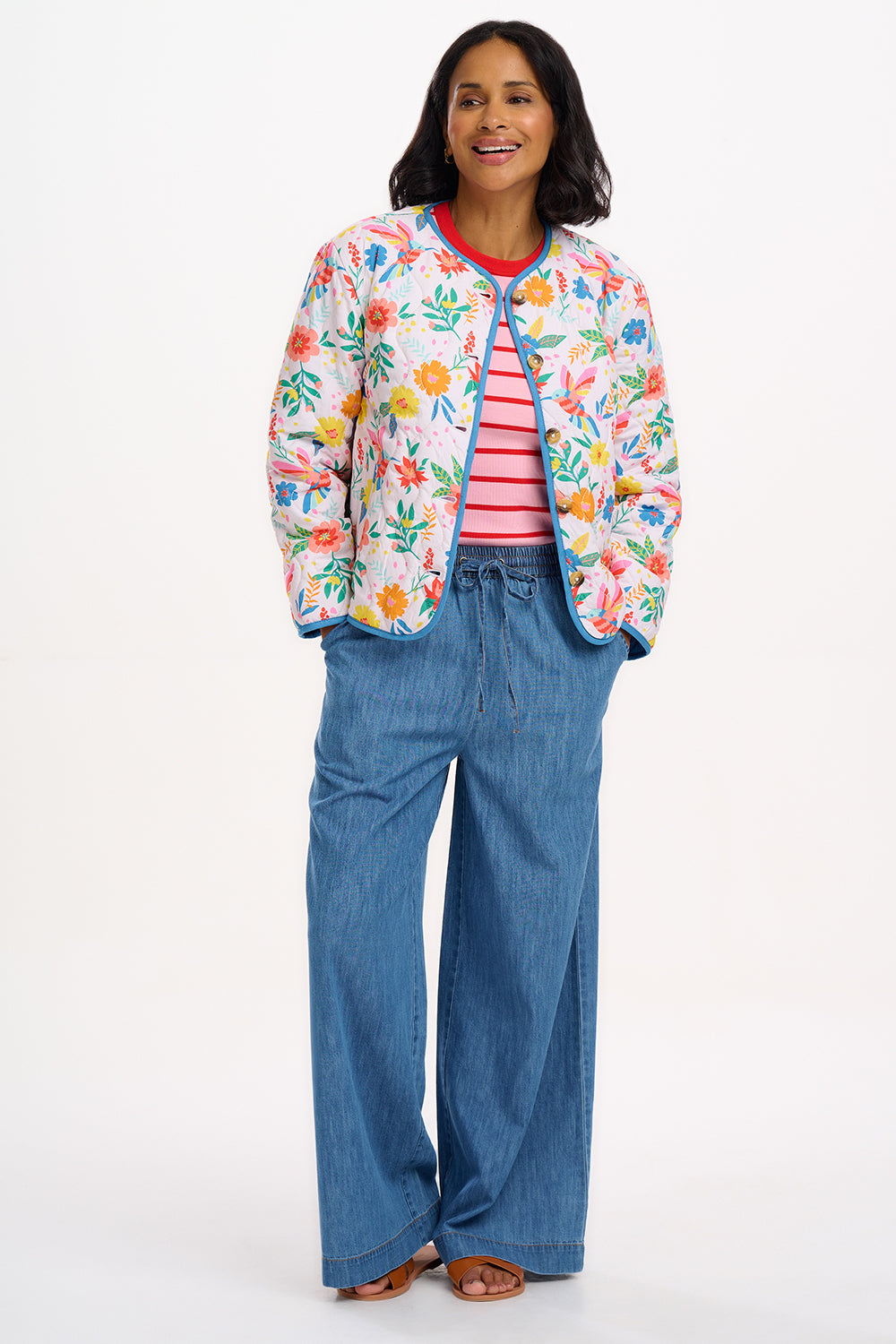 A woman wearing an off-white quilted jacket with a Tropical Hummingbird print, featuring front pockets and a round neckline.