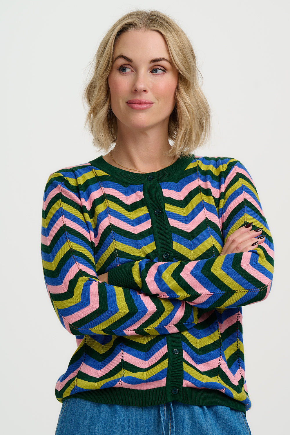 Woman wearing a colourful chevron-patterned sweater and blue jeans on a white background