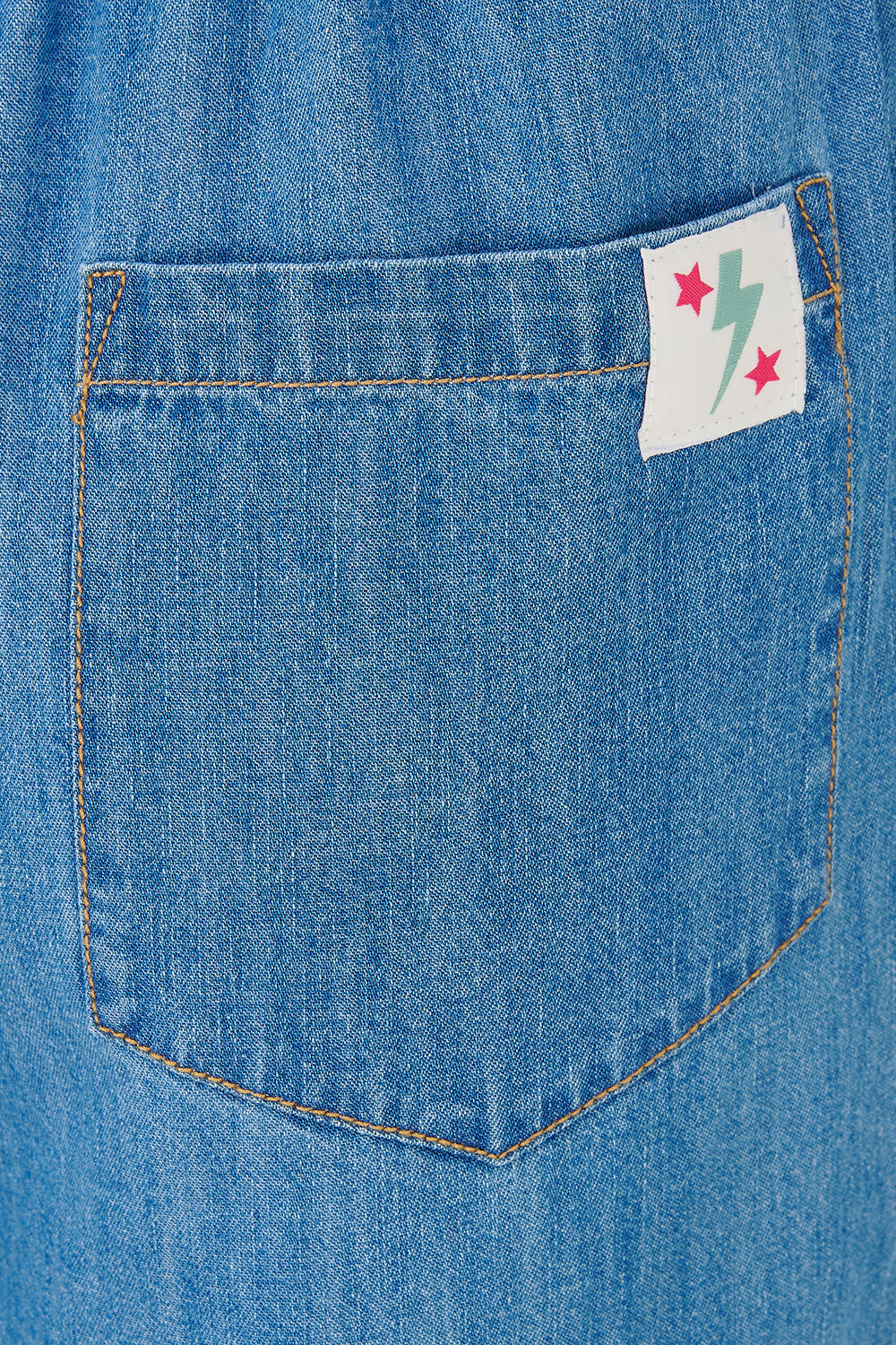 A model wearing mid blue denim wide leg trousers with an elasticated drawstring waist and back patch pockets.