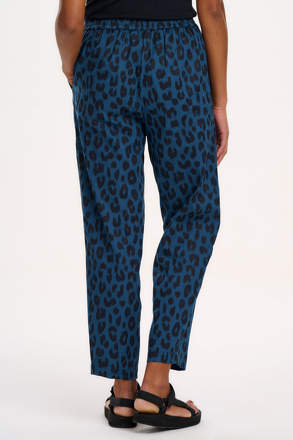 A woman modeling Romney trousers with a petrol navy color and a leopard print design.
