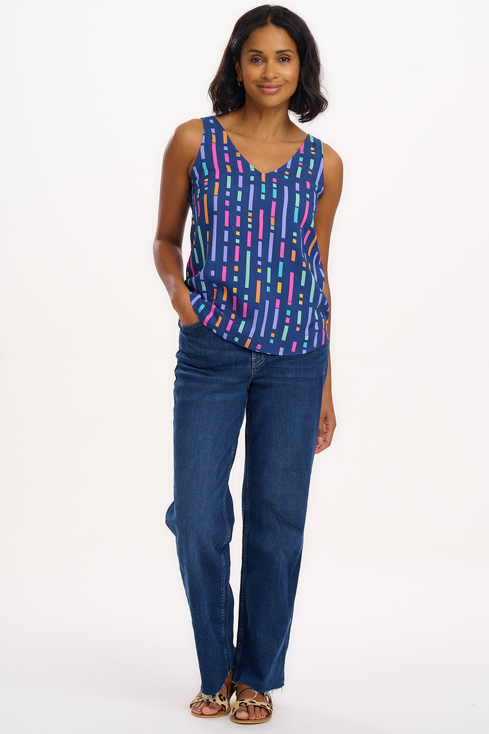 A model wearing a sleeveless blue vest top with a geometric pattern of broken lines in shades of purple, pink, green, and orange.