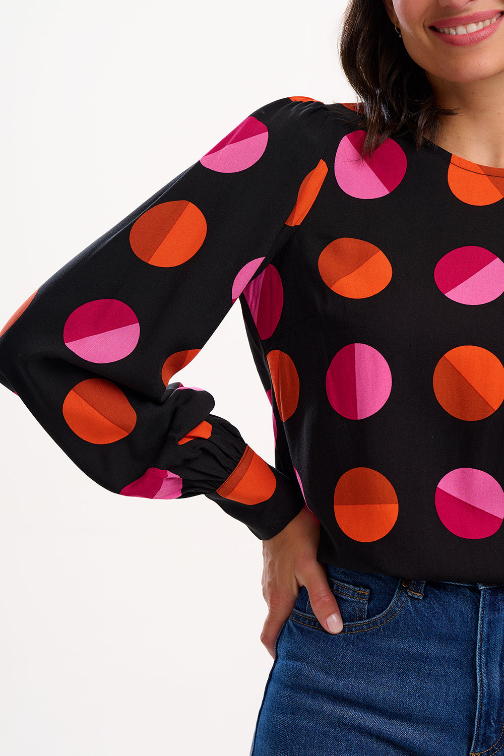 Person wearing a black sweater with colorful polka dot pattern on a white background