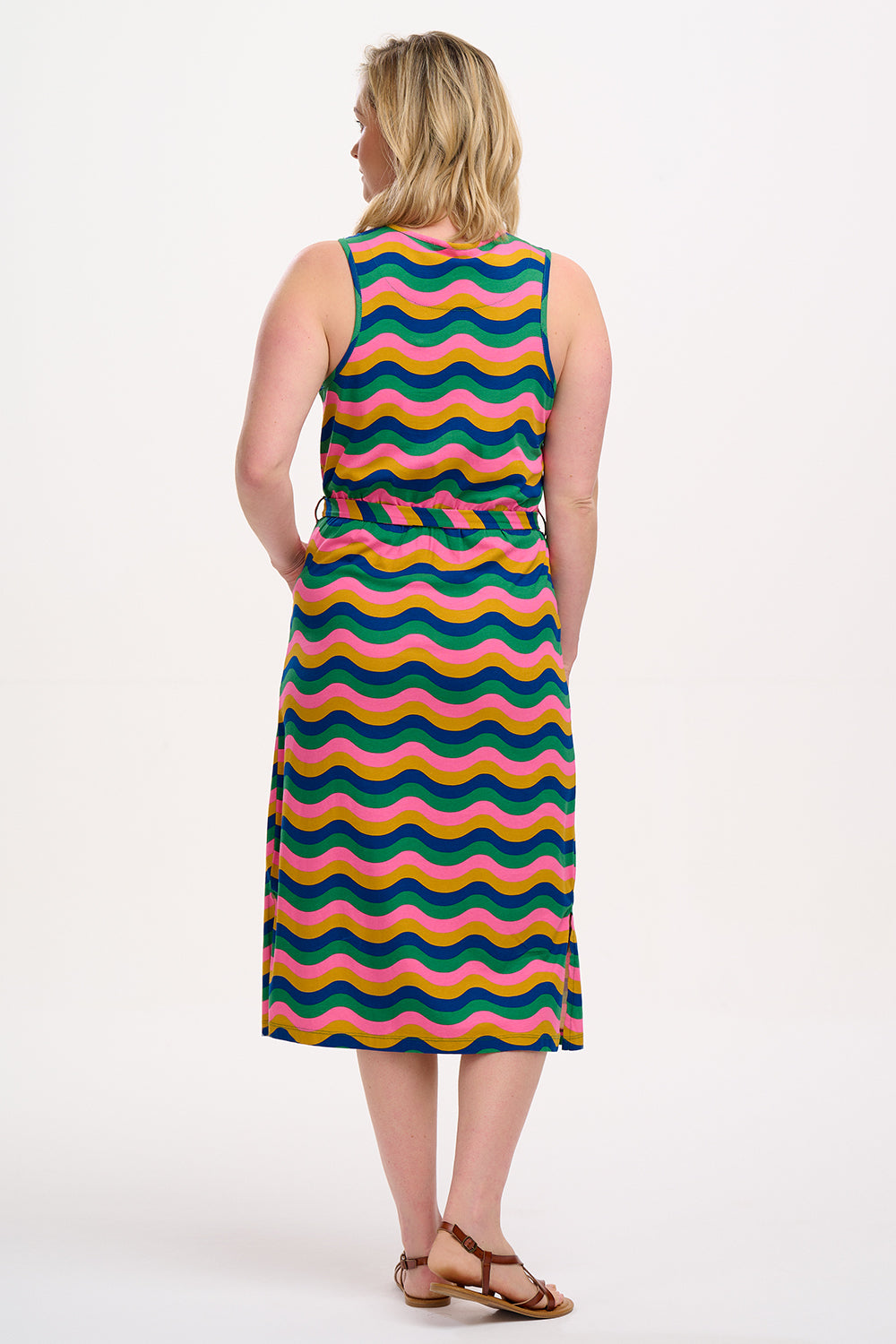 A model wearing a sleeveless, midi-length multicolor jersey dress with a wave pattern in shades of pink, green, blue, and tan.