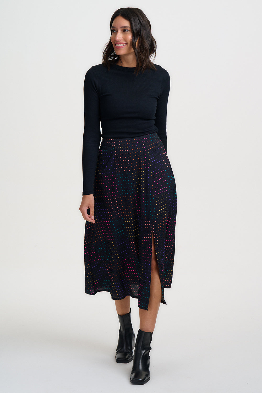 Woman wearing a black long-sleeve top and patterned skirt on a white background