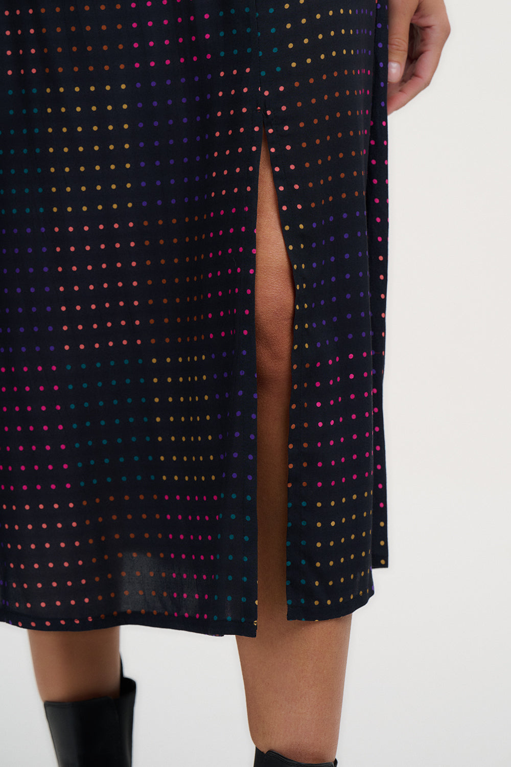Close-up of a black dress with colorful polka dots and a high slit on a white background