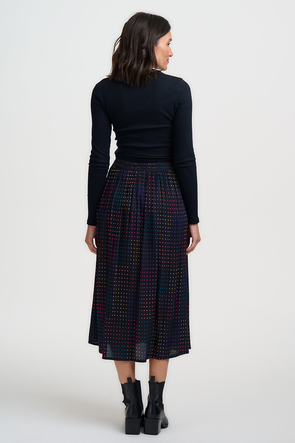 Woman wearing a black top and patterned skirt on a white background