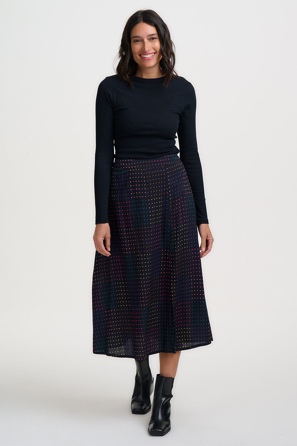 Woman wearing a black long-sleeve top and patterned skirt on a white background