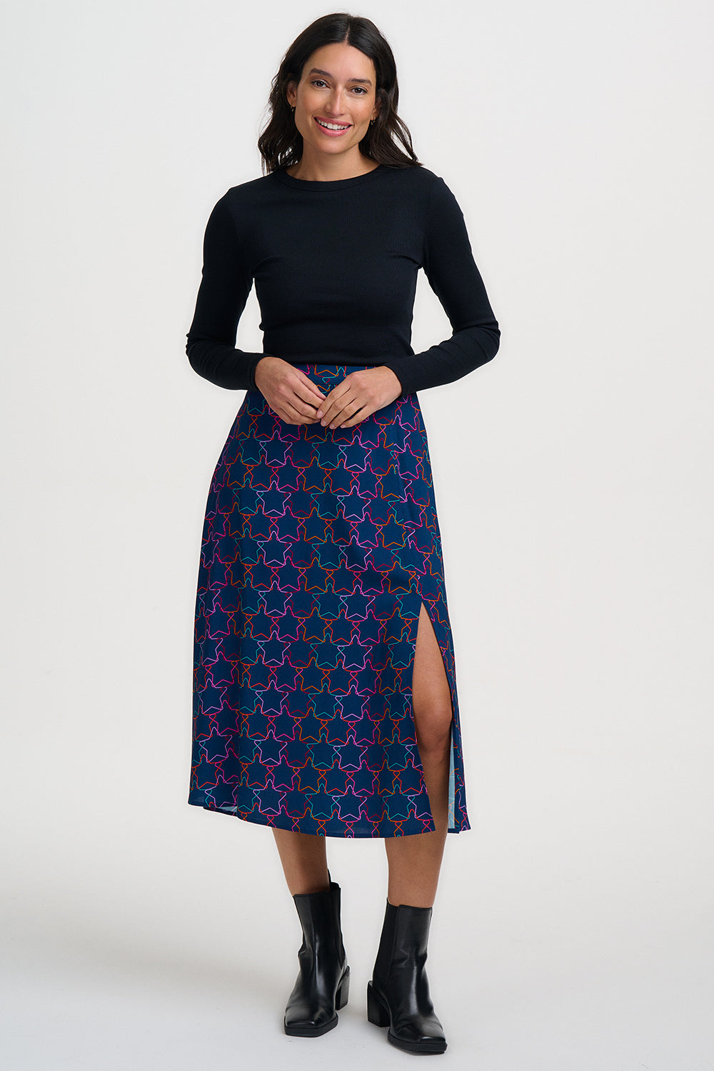 Woman wearing a black top and blue patterned skirt on a white background