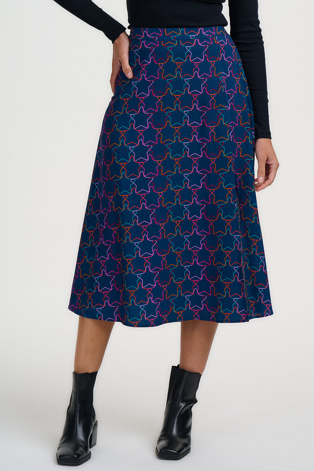 Person wearing a blue patterned skirt with black top and boots on a white background