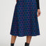 Person wearing a blue patterned skirt with black top and boots on a white background
