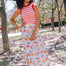 A woman wearing an off-white skirt with a tropical hummingbird print, paired with a red and white striped top.