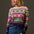 Woman wearing a colorful patterned sweater against a plain background