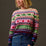 Woman wearing a colorful patterned sweater against a plain background
