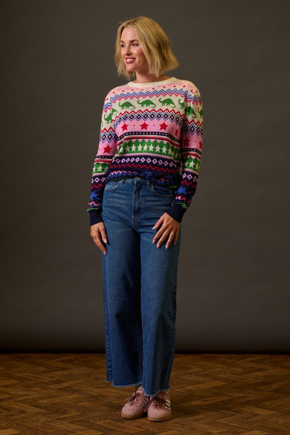 Woman wearing a colorful sweater and blue jeans against a plain background
