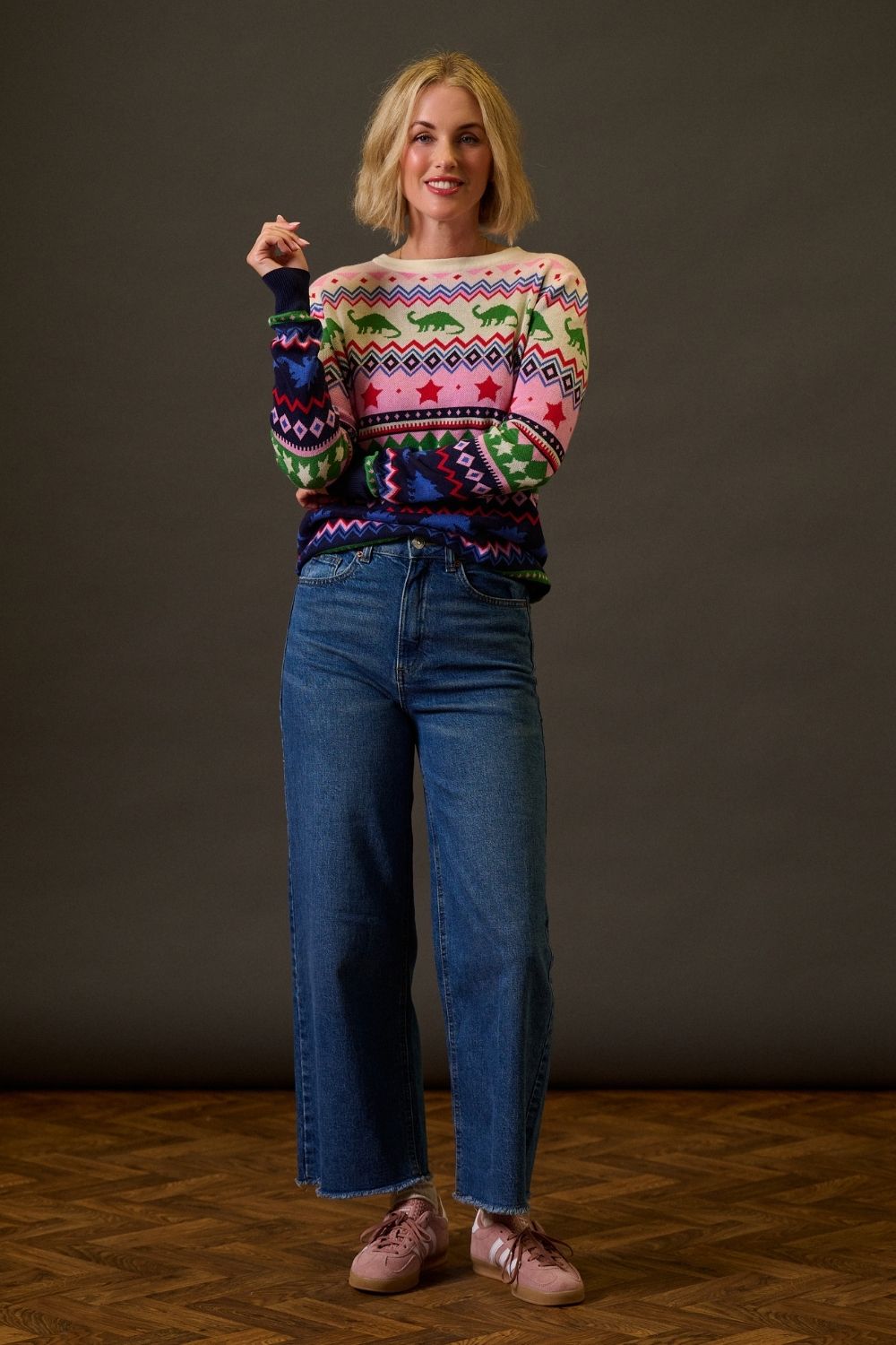 Woman wearing a colorful sweater and blue jeans against a plain background