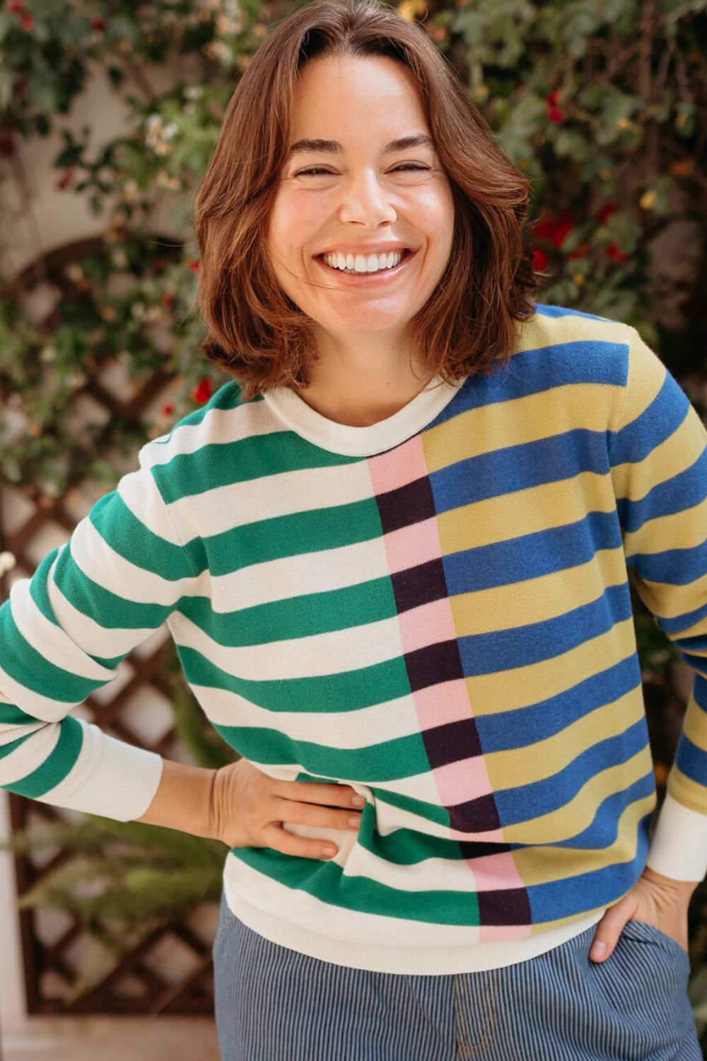 Woman wearing a colorful striped sweater with a blurred natural background