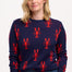 A person wearing a navy crew neck jumper with a bold lobster repeat pattern in red.