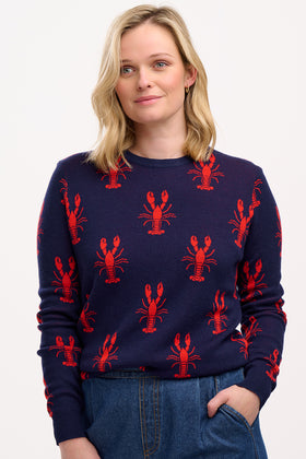 A person wearing a navy crew neck jumper with a bold lobster repeat pattern in red.