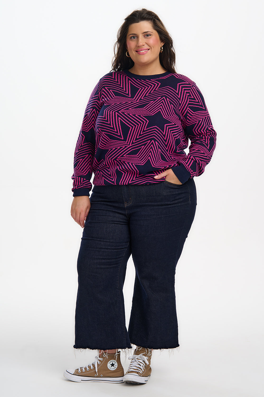 Person wearing a purple star-patterned sweater and dark jeans on a white background
