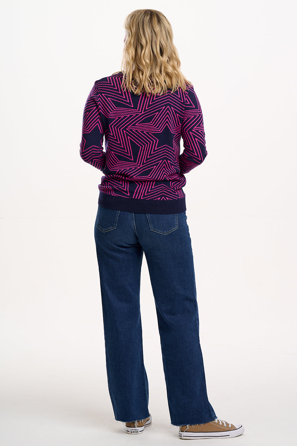 Person wearing a patterned sweater and blue jeans on a white background