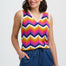 Woman wearing a colorful zigzag patterned sleeveless top with blue pants on a white background