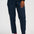 A person wearing dark navy pinstriped trousers, styled with a black top, red socks, and white sneakers with gold stripes, shown from the waist down on a light gray studio background.