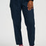 A person wearing dark navy pinstriped trousers, styled with a black top, red socks, and white sneakers with gold stripes, shown from the waist down on a light gray studio background.