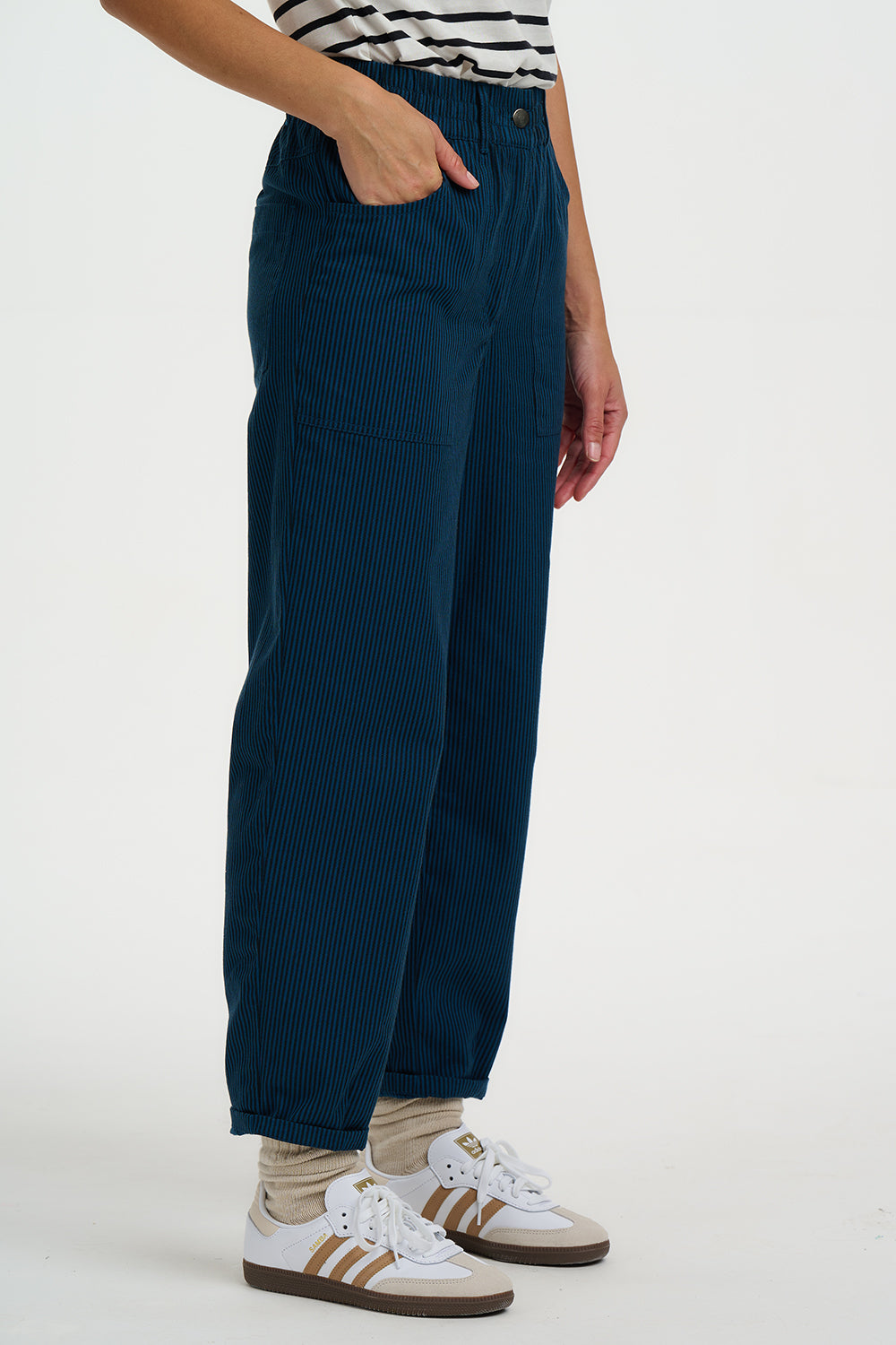 Person wearing navy corduroy pants with a white background