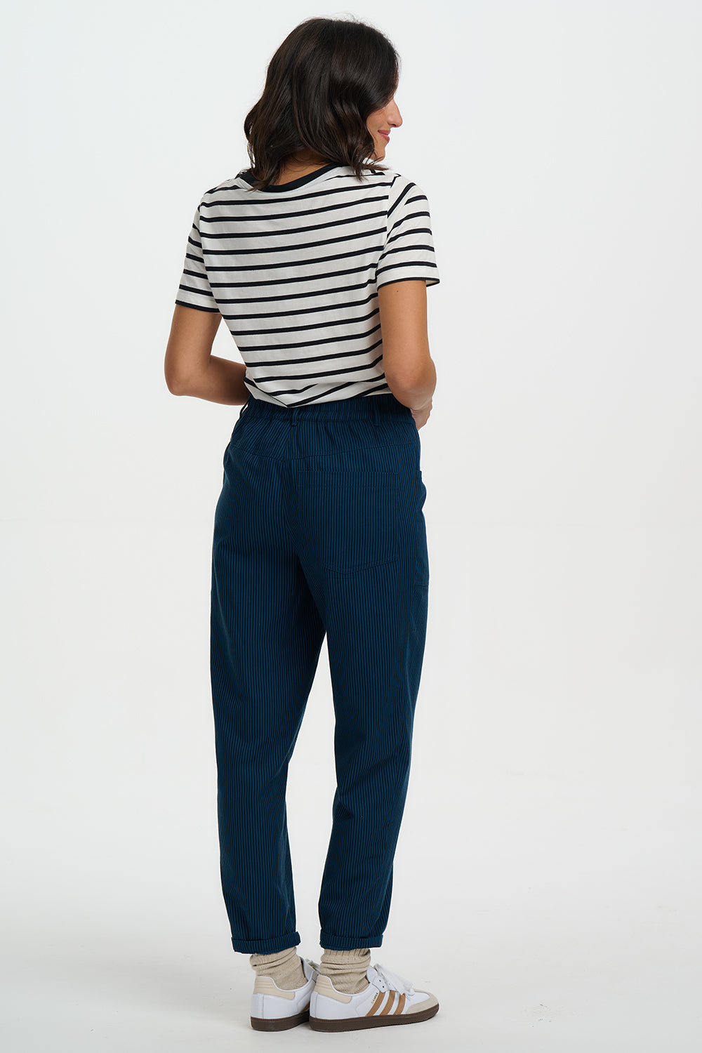 Person wearing a striped shirt and blue pants on a white background