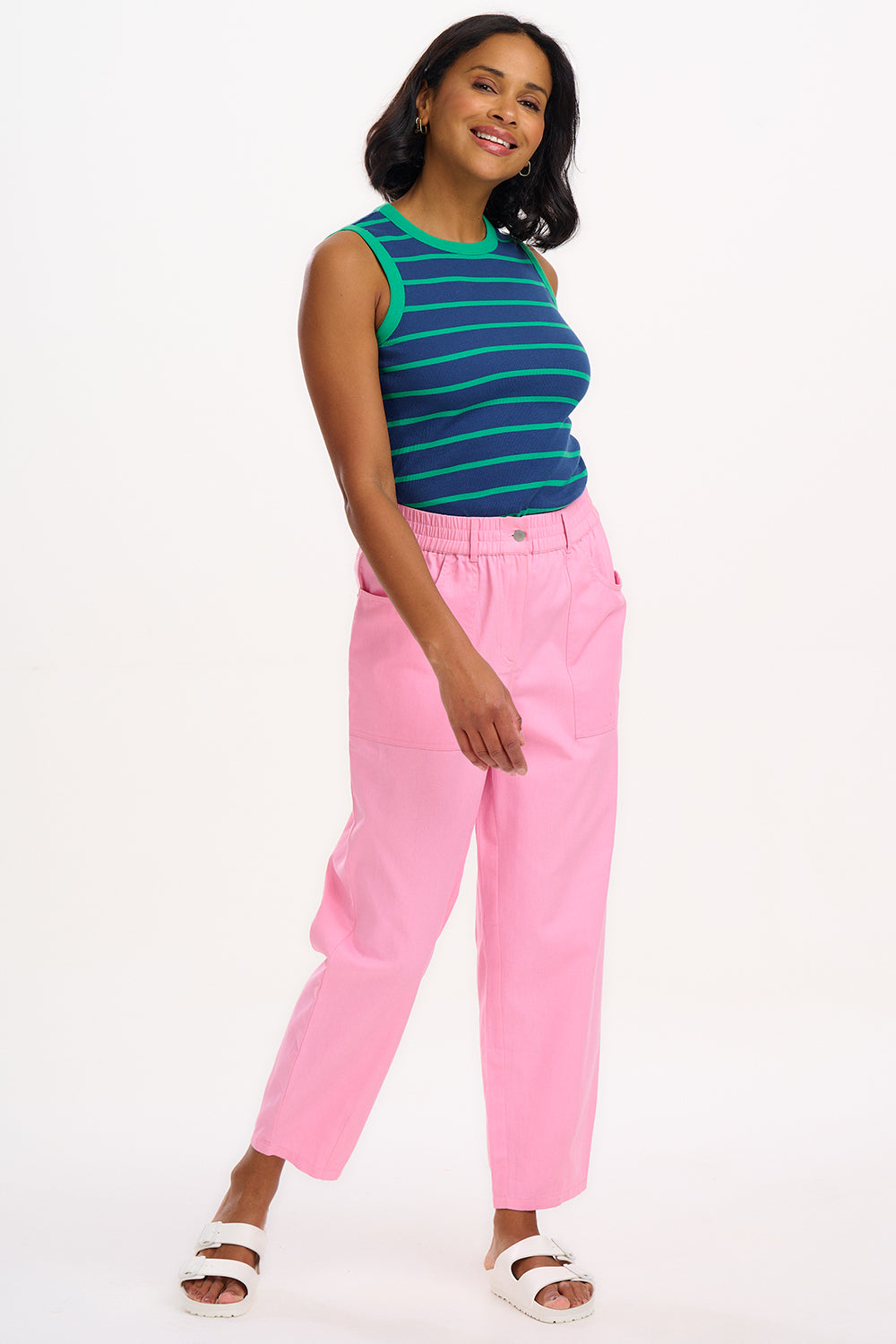 A model wearing pink Rowan trousers with a triple star pattern, paired with a striped top, standing against a white background.