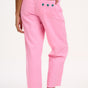 A model wearing pink Rowan trousers with a triple star pattern, paired with a striped top, standing against a white background.