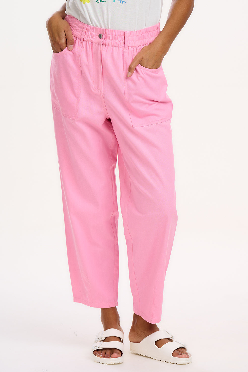 A model wearing pink Rowan trousers with a triple star pattern, paired with a striped top, standing against a white background.