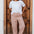 Woman wearing a white t-shirt with a red heart design and patterned pants standing in front of a wooden door.