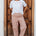 Woman wearing a white t-shirt with a red heart design and patterned pants standing in front of a wooden door.