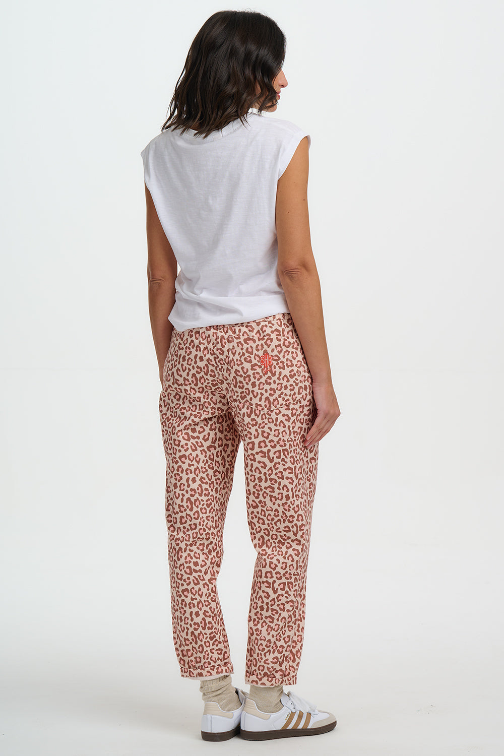Person wearing a white sleeveless top and red leopard print pants on a white background